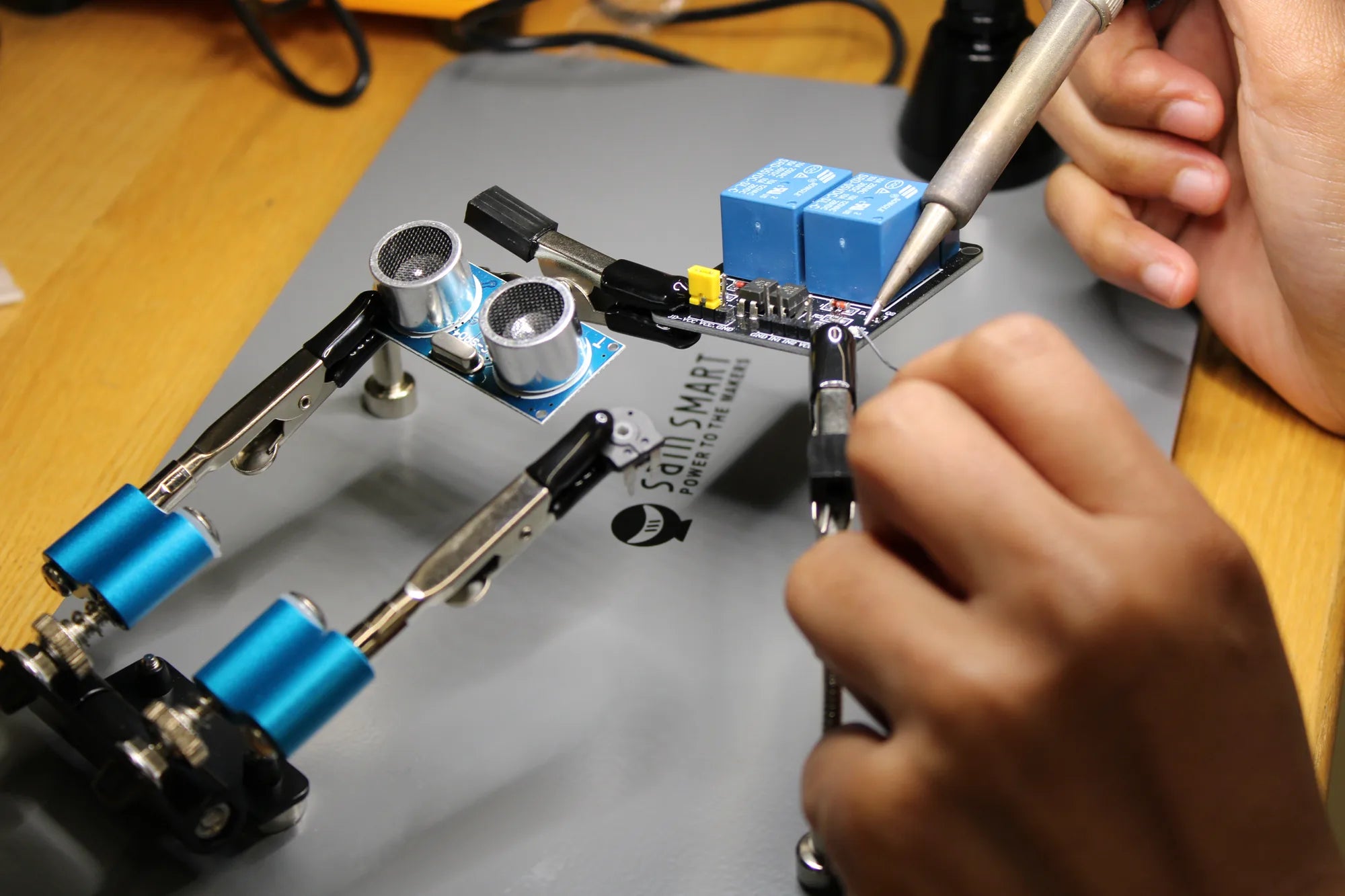 POSM student soldering a circuit board held by the SainSmart magnetic helping-hands station