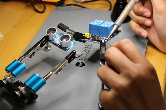 POSM student soldering a circuit board held by the SainSmart magnetic helping-hands station