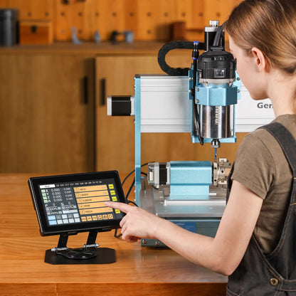 A woman in overalls stands at a workbench interacting with a touchscreen controller in front of a CNC router, with a workshop visible in the background.